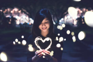 Photo of woman holding a well lit wire heart.