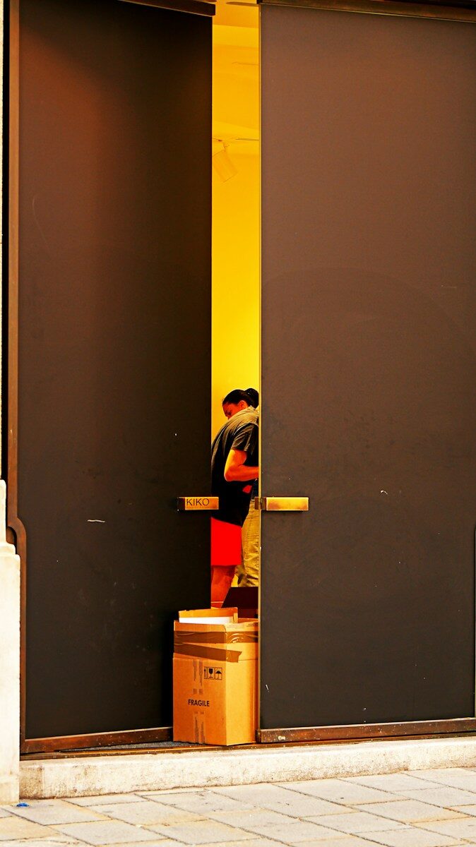 Two people stand near a doorway with boxes