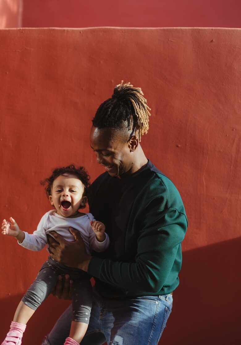 smiling man carrying child and playing