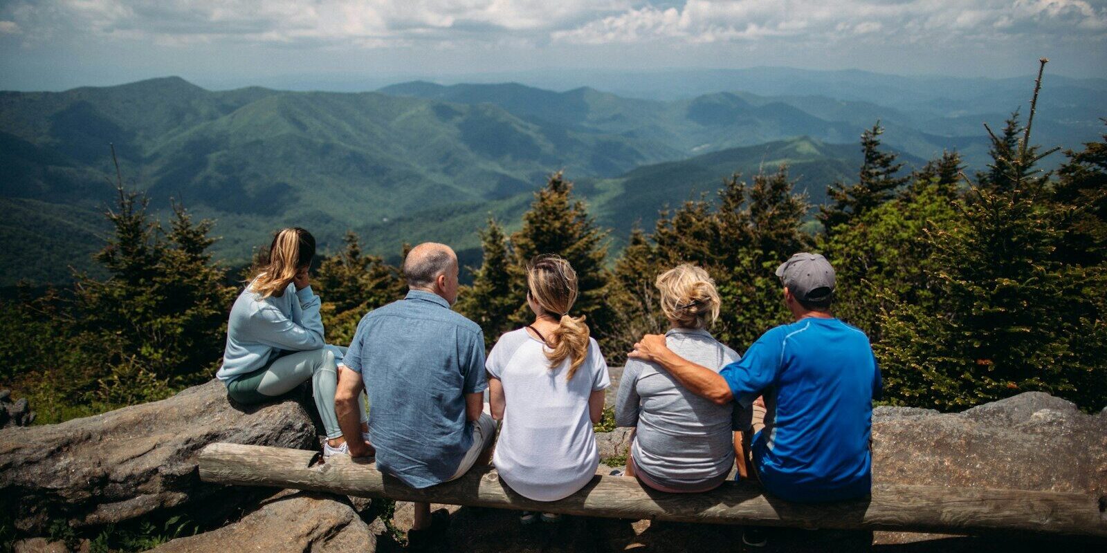 group of people sitting on rocks overlooking mountain